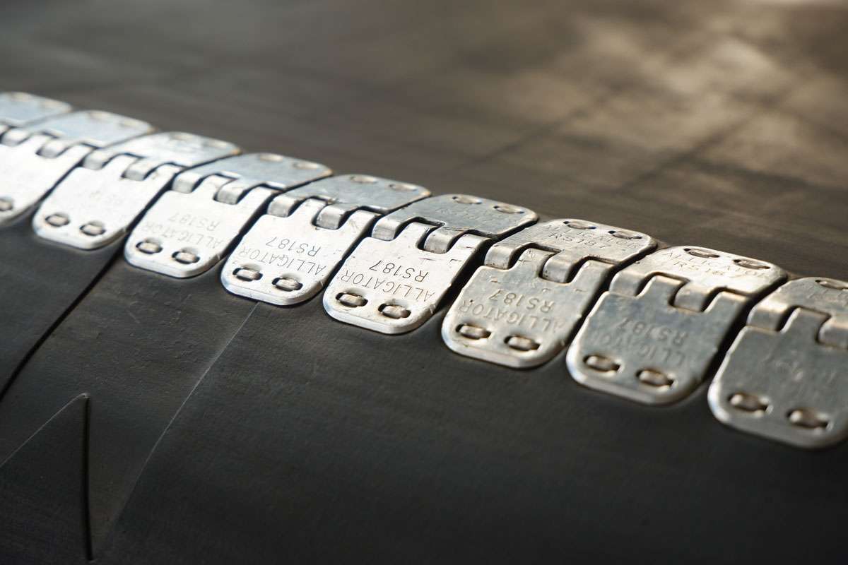 Close-up of a rubber conveyor belt connected by a flexible metal joint.Selective focus.